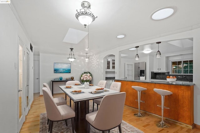 dining room featuring a skylight and light hardwood / wood-style flooring