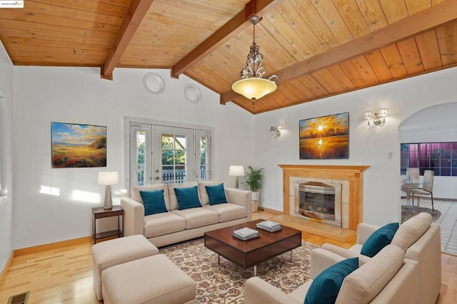 living room featuring lofted ceiling with beams, a tile fireplace, wood ceiling, and light hardwood / wood-style flooring