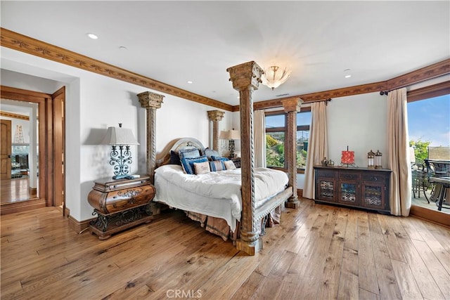 bedroom featuring light hardwood / wood-style floors, ornamental molding, decorative columns, and access to exterior