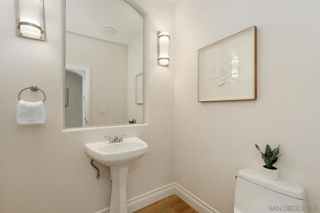 bathroom with wood-type flooring, sink, and toilet