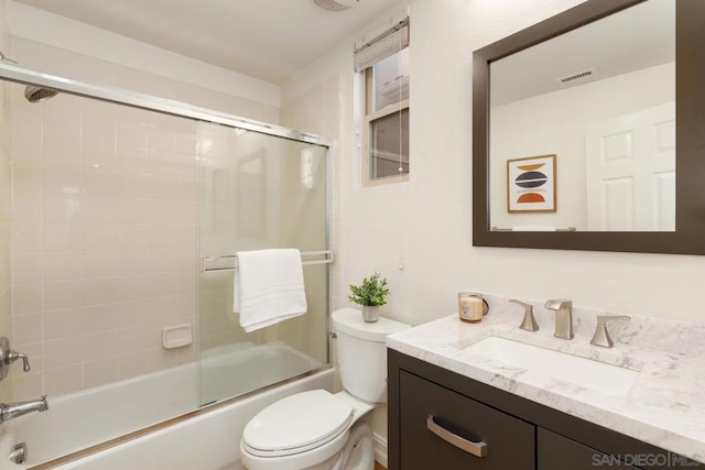 full bathroom with shower / bath combination with glass door, vanity, and toilet