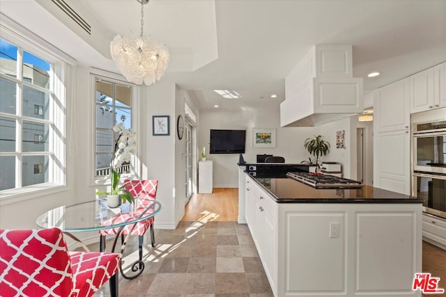 kitchen with stainless steel appliances, white cabinets, a raised ceiling, pendant lighting, and plenty of natural light