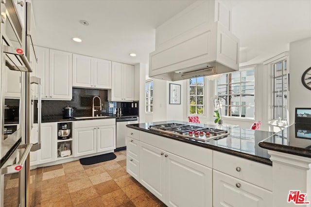 kitchen with appliances with stainless steel finishes, white cabinetry, backsplash, and sink