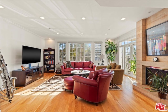 living room with a large fireplace, hardwood / wood-style flooring, and ornamental molding