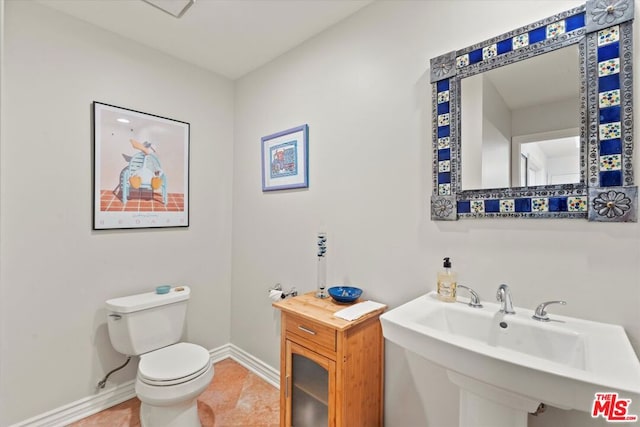 bathroom with toilet, tile patterned flooring, and sink