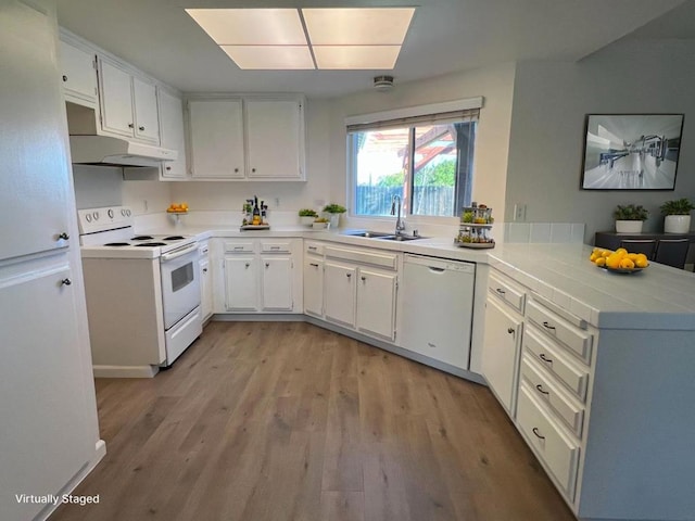 kitchen with sink, white cabinets, white appliances, light hardwood / wood-style floors, and kitchen peninsula