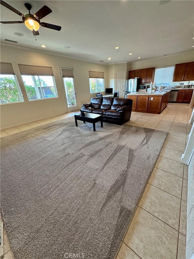 tiled living room with ceiling fan and crown molding