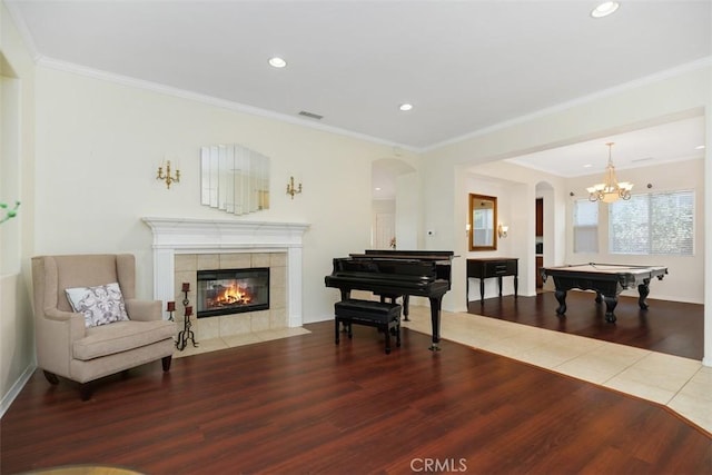 sitting room with hardwood / wood-style flooring, a chandelier, crown molding, and a fireplace