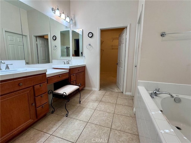 bathroom with vanity, tile patterned flooring, and tiled tub