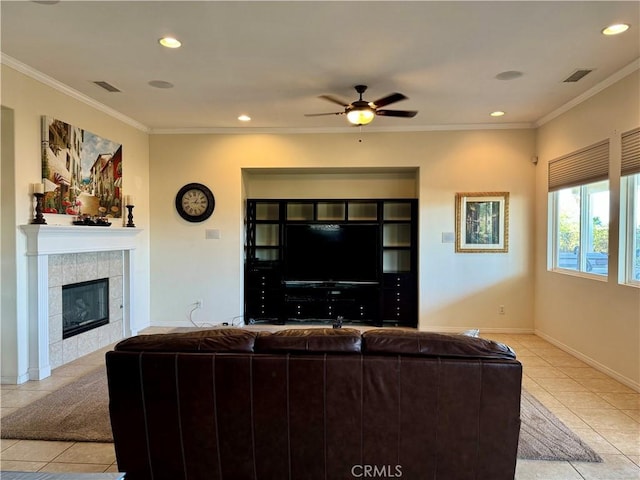 living room with a tile fireplace, ceiling fan, ornamental molding, and light tile patterned floors