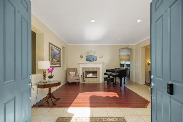 entrance foyer with ornamental molding, light tile patterned flooring, and a fireplace