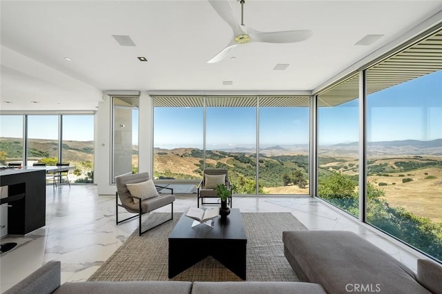 sunroom / solarium featuring ceiling fan and a mountain view