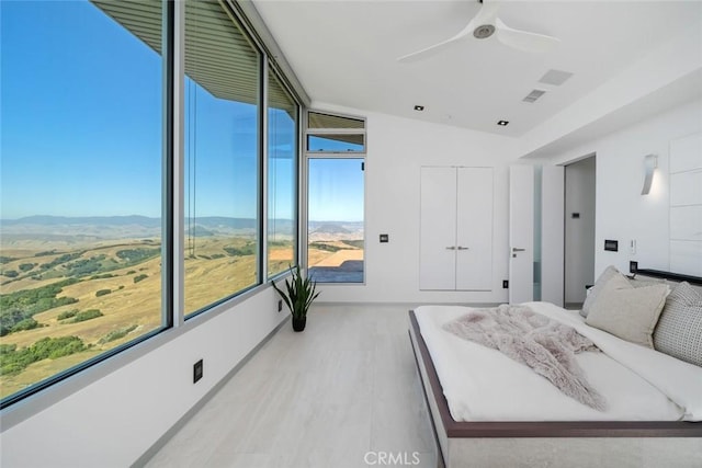 bedroom featuring ceiling fan, vaulted ceiling, a mountain view, and light hardwood / wood-style flooring