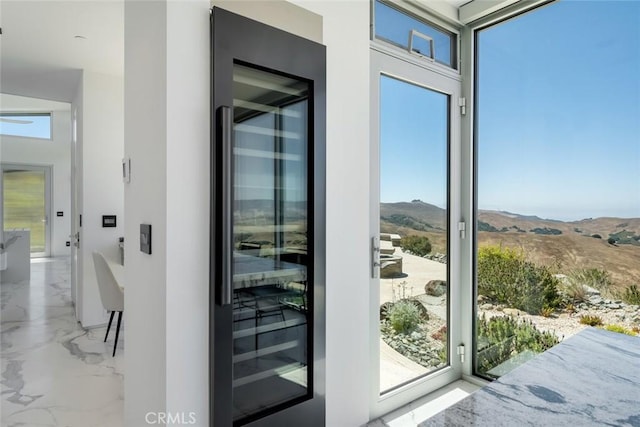 doorway to outside with wine cooler, a mountain view, and plenty of natural light