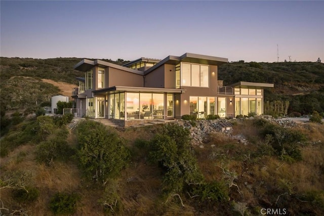 back house at dusk featuring a sunroom