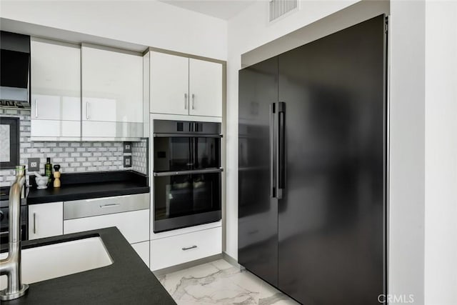 kitchen with decorative backsplash, sink, white cabinets, and black appliances