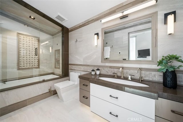 full bathroom featuring tile walls, combined bath / shower with glass door, vanity, and toilet