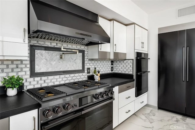 kitchen featuring backsplash, white cabinets, black appliances, and wall chimney exhaust hood