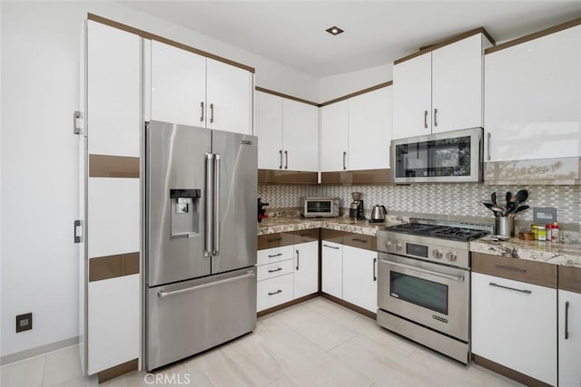 kitchen featuring white cabinetry, stainless steel appliances, tasteful backsplash, light tile patterned flooring, and light stone counters