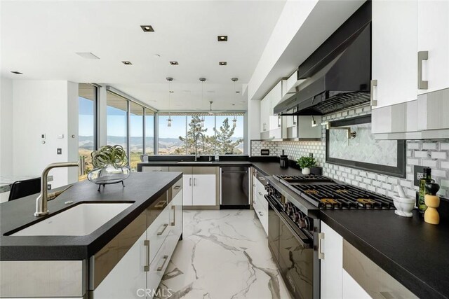 kitchen with white cabinetry, a mountain view, gas stove, wall chimney range hood, and sink