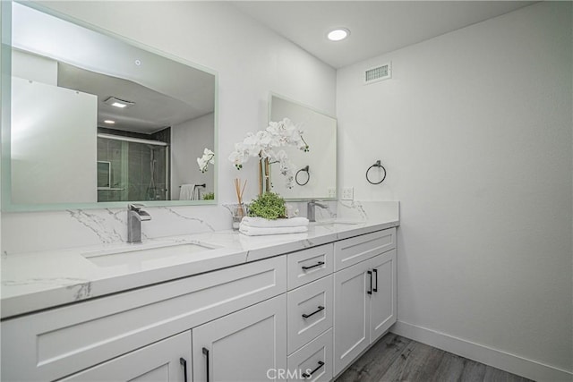 bathroom with a shower with shower door, vanity, and wood-type flooring