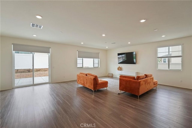 living room featuring a wealth of natural light and dark wood-type flooring