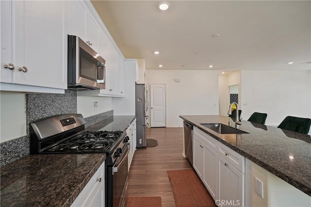 kitchen with sink, stainless steel appliances, white cabinets, and dark stone countertops