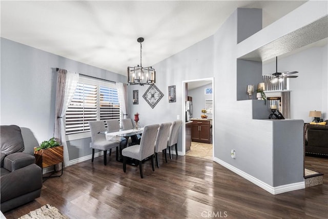 dining room featuring ceiling fan with notable chandelier, dark hardwood / wood-style floors, and vaulted ceiling