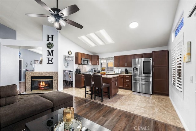 living room featuring ceiling fan, light hardwood / wood-style flooring, and vaulted ceiling