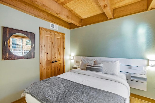 bedroom with wooden ceiling, a closet, hardwood / wood-style floors, and beamed ceiling