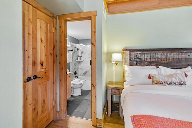 bedroom featuring ensuite bath and hardwood / wood-style flooring