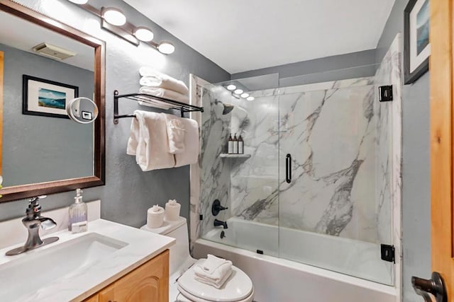 full bathroom with bath / shower combo with glass door, vanity, and toilet