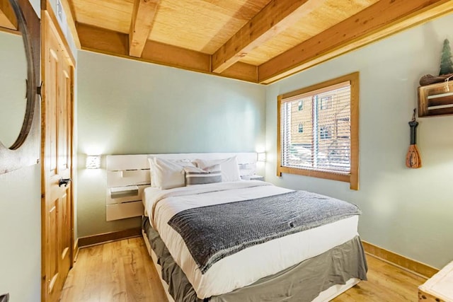 bedroom featuring light wood-type flooring, beam ceiling, a closet, and wood ceiling