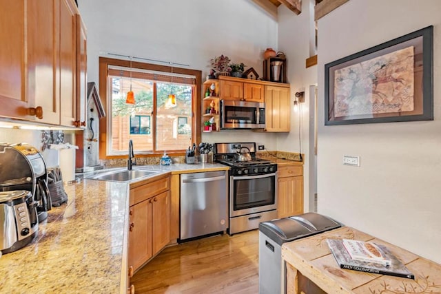 kitchen featuring light stone counters, stainless steel appliances, light hardwood / wood-style floors, beamed ceiling, and sink