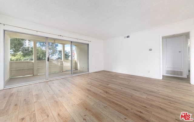 spare room with a textured ceiling and light hardwood / wood-style floors