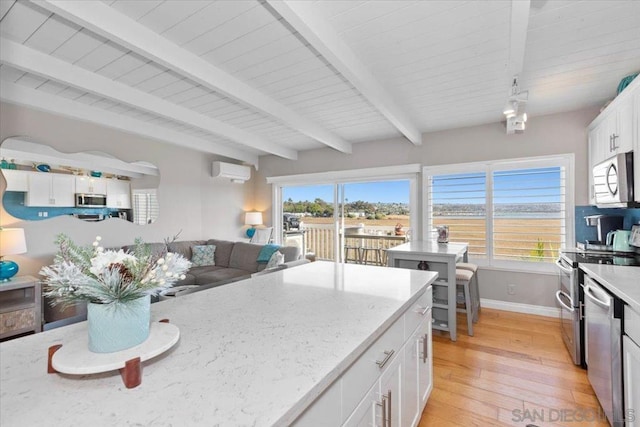 kitchen featuring light stone countertops, a wall unit AC, white cabinetry, and appliances with stainless steel finishes