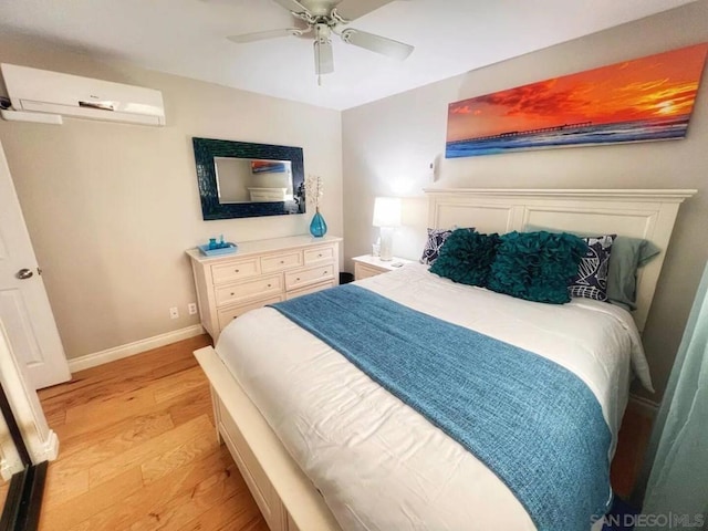 bedroom featuring ceiling fan, a wall mounted AC, and light wood-type flooring