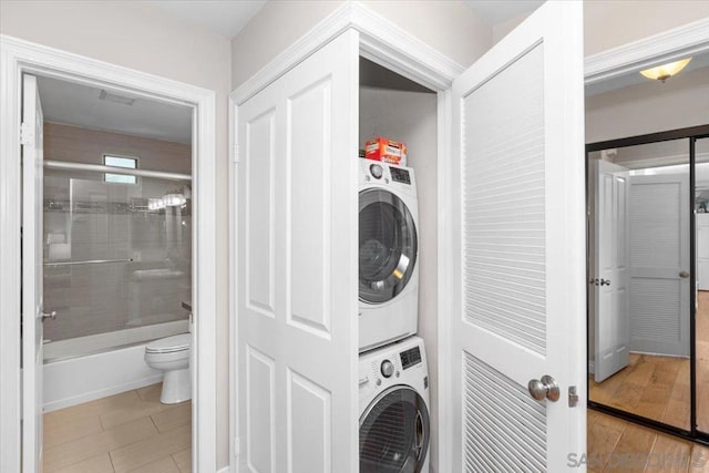 laundry room featuring stacked washer / drying machine and light tile patterned floors