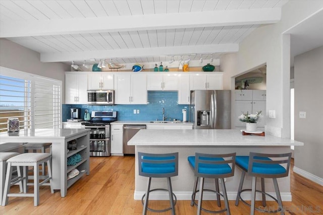 kitchen with white cabinets, stainless steel appliances, sink, and a kitchen breakfast bar