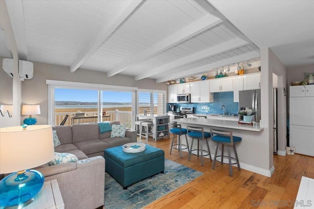 living room featuring sink, beamed ceiling, light hardwood / wood-style floors, and a wall mounted air conditioner