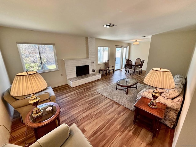 living room featuring a brick fireplace and wood-type flooring