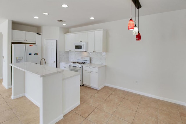 kitchen with white appliances, a center island with sink, light stone countertops, white cabinetry, and backsplash