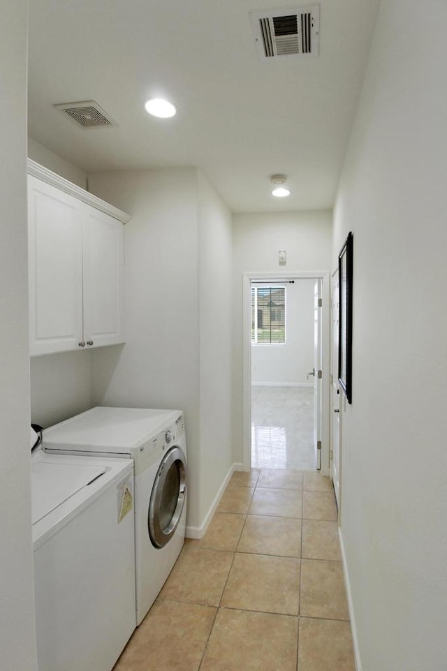 laundry room with light tile patterned floors, separate washer and dryer, and cabinets