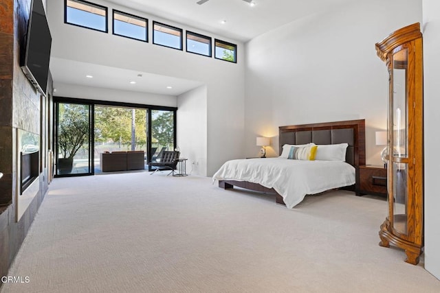 carpeted bedroom with a towering ceiling and access to exterior