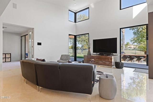 living room featuring a towering ceiling and a healthy amount of sunlight