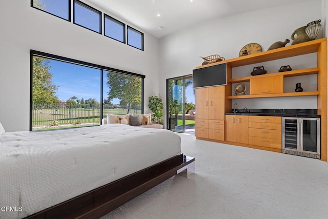 carpeted bedroom with a towering ceiling, multiple windows, bar area, and wine cooler