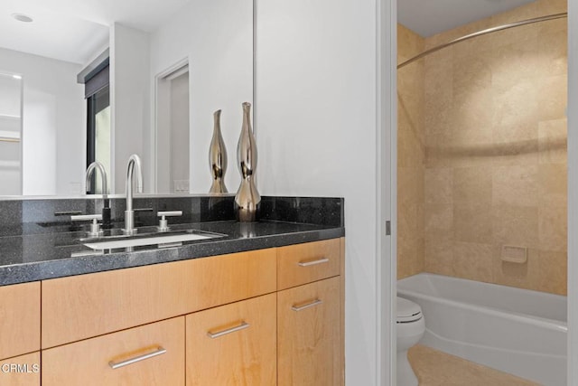 full bathroom featuring vanity, tiled shower / bath combo, and toilet