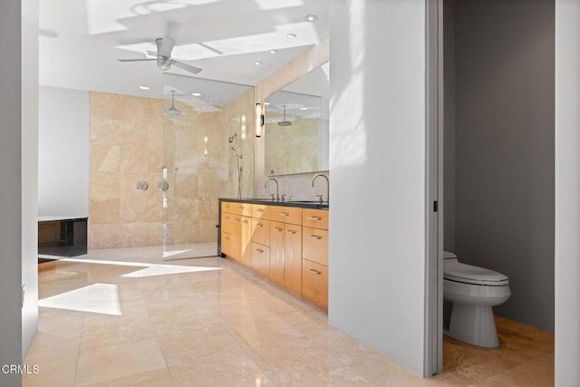 bathroom featuring toilet, a tile shower, ceiling fan, and vanity