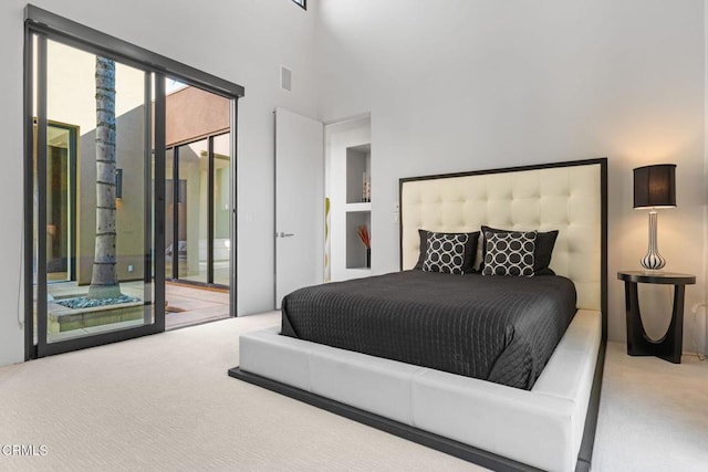 bedroom featuring a towering ceiling, light colored carpet, and access to exterior