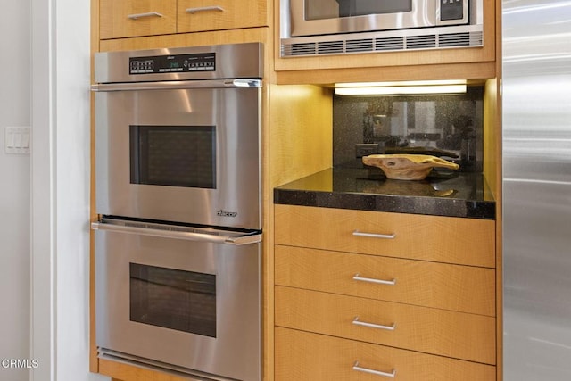 kitchen with stainless steel appliances, decorative backsplash, and dark stone countertops